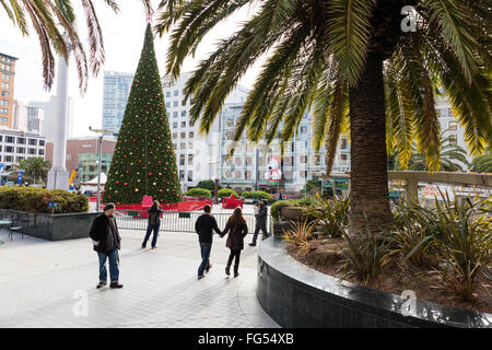 Junges Paar Hand in Hand- und Wanderwege durch einen Weihnachtsbaum am Union Square in San Francisco, CA Stockfoto