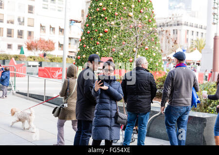 Junge asiatische Frau trägt einen Winter Mantel, wobei eine Selfie / Foto auf der Vorderseite des Weihnachtsbaumes am Union Square Stockfoto