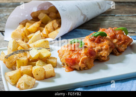 Kabeljau mit Tomatensauce und tiefen Bratkartoffeln auf Tablett Stockfoto