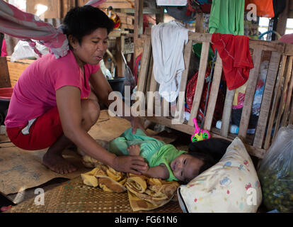 Eine philippinische Frau neigt dazu, ein Baby in den Kohlenstoffmarkt befindet sich im Zentrum von Cebu City, Philippinen Stockfoto