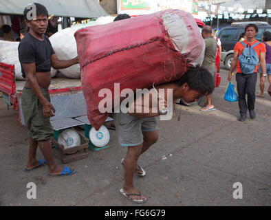 Eine schwere Last getragen von einem philippinischen Mann innerhalb der CO2-Markt befindet sich im Zentrum von Cebu City, Philippinen Stockfoto