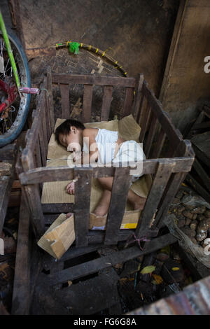 Ein Kind schläft in einem provisorischen hölzernen Babybett innerhalb der CO2-Markt befindet sich im Zentrum von Cebu City, Philippinen Stockfoto