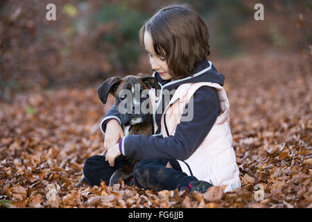 Boxer Welpen sitzen mit kleinen Mädchen im Herbst Blätter Stockfoto