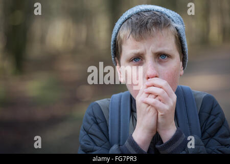 Ein kalter junge in den Wäldern um warm zu halten versuchen Stockfoto