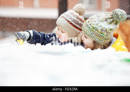 Mutter mit Kind spielen im Schnee auf Winterspaziergang, positive Emotionen, im Freien. Schneefall, Blizzard. Stockfoto