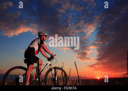 Mann mit dem Fahrrad auf den Sonnenuntergang im freien Stockfoto