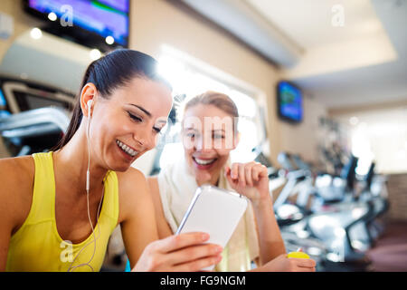 Passen zwei attraktive Frauen im Fitness-Studio mit Smartphone Stockfoto