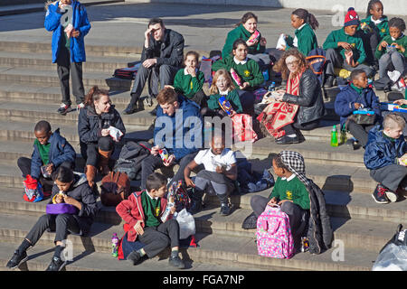 London, Trafalgar Square A Primary School Party zu Mittag auf den Stufen des Platzes Stockfoto