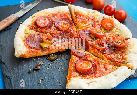 Pizza mit Salami Fleisch, Cherry-Tomaten und Oregano Gewürz Stockfoto