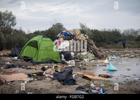 Müll sammelt sich neben eine große Pfütze im schlammigen Umfeld der Dschungel-Flüchtlingslager in Calais, Frankreich. Stockfoto