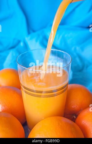 in ein Glas gefüllt mit Orangensaft auf blauem Hintergrund Stockfoto