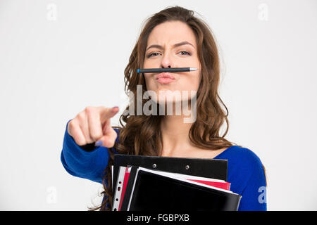 Lustige junge Frau mit Ordnern Simitating Schnurrbart mit Stift und zeigen vor der Kamera auf weißem Hintergrund Stockfoto