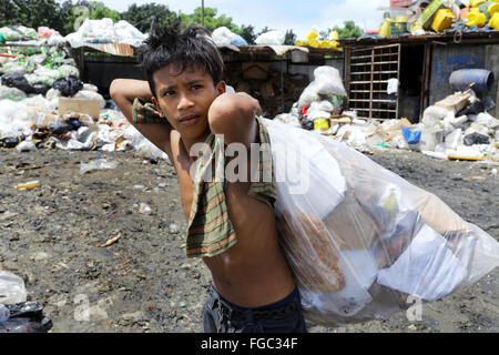 Junge (14) arbeitet in einer Mülltrennung und Weiterverkauf in einem Junk-e-Shop in der Nähe der Quezon City integrierte verschwenden Endlagers in Barangay (Dorf) Payatas in Quezon Stadt, Metro Manila, Philippinen Stockfoto