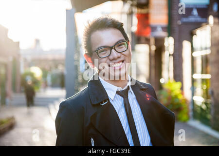 Junge asiatische Mann tragen Brillen und Business Kleidung auf Stadtstraße am späten Nachmittag Stockfoto