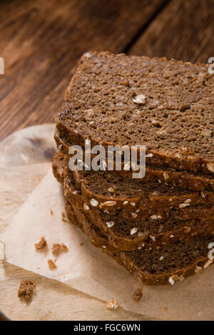 Schwarzbrot (in Scheiben geschnitten) auf einem alten Holztisch (Tiefenschärfe) Stockfoto