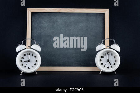 Zwei Vintage Wecker zeigt 9 und 05:00 mit leeren Tafel auf schwarzem Hintergrund. Neun bis fünf corporate Arbeitszeiten Stockfoto