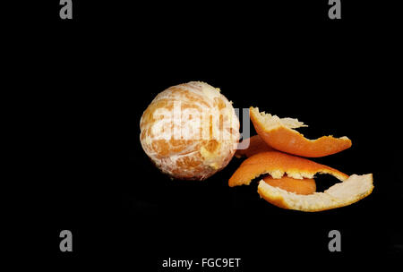 Eine geschälte ganze Nabel Orange mit Peelings, citrus X sinensis, auf einem schwarzen Hintergrund. Stockfoto