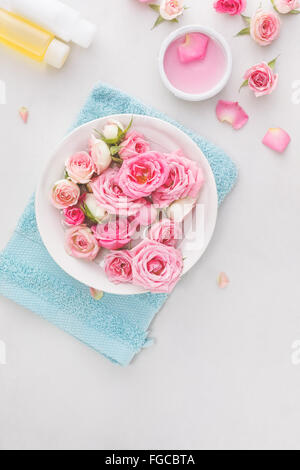 Spa-Einstellungen mit Rosen. Frische Rosen und Rosenblätter in eine Schüssel mit Wasser und verschiedene Gegenstände, die für die Spa-Behandlungen Stockfoto