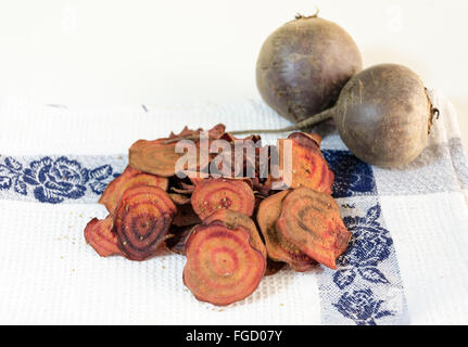 Dünne runde rote Beete Chips gebacken im Ofen mit Oregano, Salz und Reife Rüben Wurzeln auf einem Küchentuch isoliert in weißen Zeitmessung Stockfoto