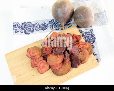 Dünne runde rote Beete Chips gebacken im Ofen mit Oregano, Salz und Reife Rüben Wurzeln auf ein Küchentuch und Schneidebrett isoliert Stockfoto