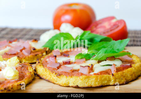 Nahaufnahme der kleine Runde gebackene Pizza aus Blumenkohl Kruste und garniert mit Speck, Schinken, Halloumi-Käse, Lountza, Tomatensauce Stockfoto