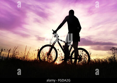 Reisende mit Fahrrad gestoppt auf Feld bei Sonnenuntergang Stockfoto