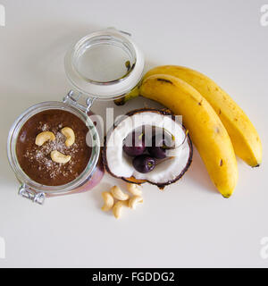 Kirsche Kokos Banane über Nacht Hafer mit gerissenen öffnen Coco, Banane, Cashew-Kerne gemischt mit Chia Samen und Kirsche Sahne in einer Mason j Stockfoto