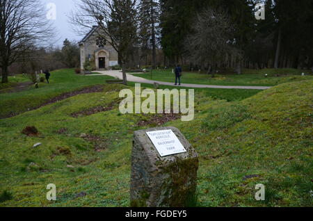 Verdun, Frankreich. 12. Februar 2016. Ein Gedenkstein erinnert an eine Farm, die in den Schlachten des 1. Weltkrieges zerstört und nicht wieder aufgebaut, in das Dorf Fleury-Devant-Douaumont bei Verdun, Frankreich, 12. Februar 2016. Im Hintergrund ist der Notre-Dame-de-l'Europezu-Gedächtniskapelle. Der 100. Jahrestag des Beginns der Schlacht ist am 21. Februar 2016. Foto: SEBASTIAN KUNIGKEIT/DPA/Alamy Live-Nachrichten Stockfoto