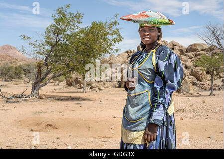 Porträt einer jungen Frau der Herero mit traditionellen Kleid und Hut außerhalb ihres Dorfes. Stockfoto