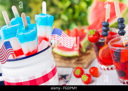 Hausgemachte rot-weiß-blauen Eis am Stiel auf einen Tisch im Freien mit erfrischenden Limonade im Hintergrund. Stockfoto