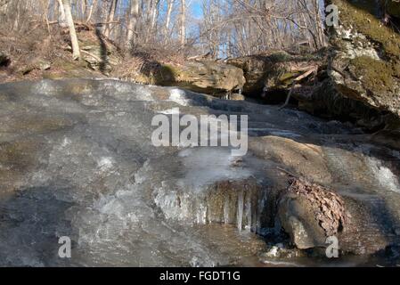 Ein Blatt des Eises drapiert über einem felsigen Hügel, Raven Rock Falls in Maryland. Stockfoto