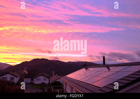 Sonnenuntergang über Häuser am Stadtrand von Ambleside, Lake District, Cumbria, UK, mit Blick auf Wetherlam, mit Solarzellen auf einem Stockfoto