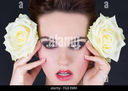 Junge Frau mit zwei gelben Rosen seitlich nex Stockfoto