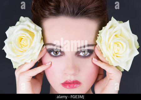 Junge Frau mit zwei gelben Rosen seitlich nex Stockfoto