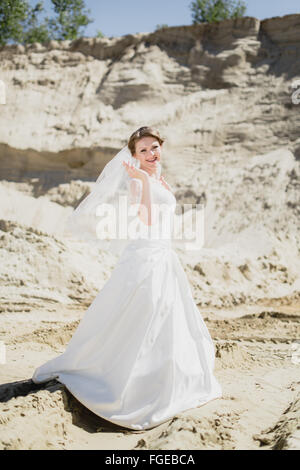 blonde Braut auf einem Sand im weißen Kleid Stockfoto