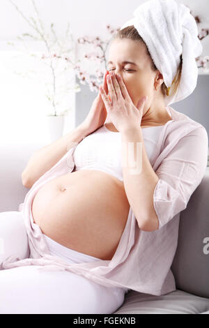 Müde in der Schwangerschaft. Schwangere Frau gähnt ruht auf dem sofa Stockfoto