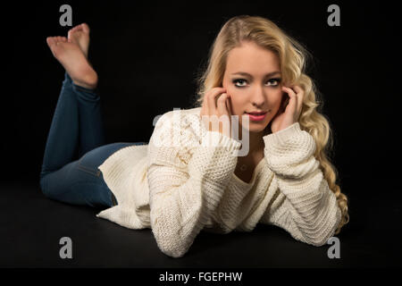 Junge, blonde Frau im weißen Pullover Stockfoto