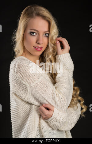 Junge, blonde Frau im weißen Pullover Stockfoto