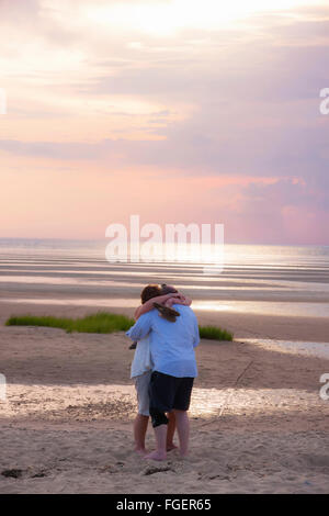 Paar am Strand bei Sonnenuntergang umarmen. Stockfoto