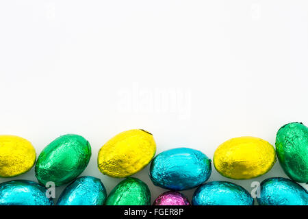 Ein Haufen von bunten, Schokolade Ostern Eier an der Unterseite des Rahmens mit Kopie Raum oben auf einem weißen Hintergrund. Stockfoto