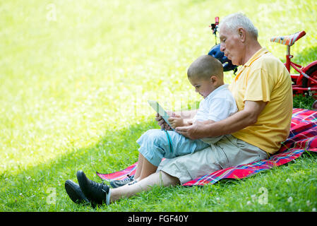 Großvater und Kind im Park mit tablet Stockfoto