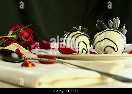 Weiße Schokolade überzogene Erdbeeren mit dunkler Schokolade Nieselregen, beleuchtete dramatisch, setzen auf eine romantische Kulisse. Stockfoto