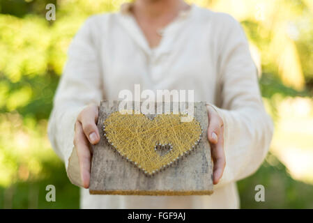 Kaukasische Mädchen symbolische Herz mit geschlossenen Händen und halben Körper anbietet Stockfoto