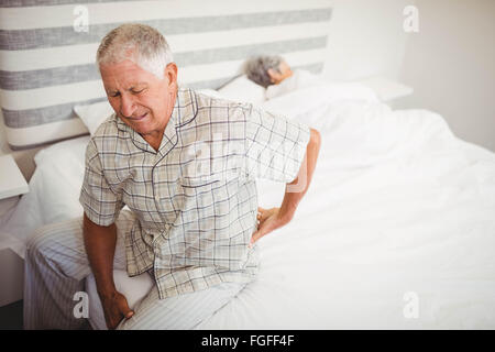 Ältere Mann leidet unter Rückenschmerzen sitzen auf Bett Stockfoto