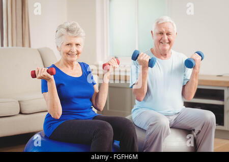 Porträt von senior paar sitzt auf Fitness-Kugeln mit Hanteln Stockfoto
