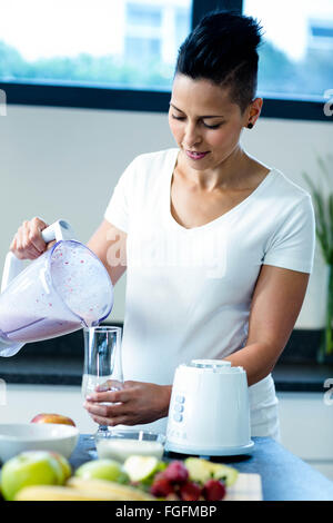 Schwangere Frau Smoothie in Glas gießen Stockfoto