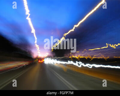 Lichtspuren der fließenden Verkehr entnommen aus einem fahrenden Auto in der Dämmerung Stockfoto