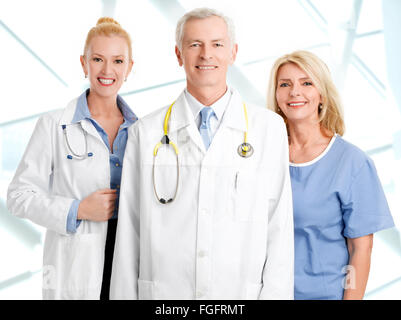 Medizinisches Personal Porträt. Ärztin und männlichen Arzt stehend mit Pflegehelferin im Krankenhaus während lächelnd und Blick auf c Stockfoto