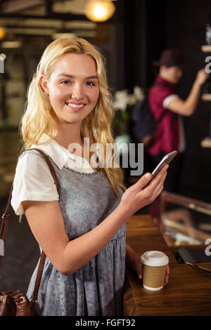 Lächelnde blonde Kaffee trinken und mit smartphone Stockfoto