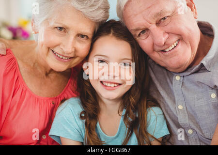 Großeltern und Enkeltochter sitzen zusammen auf sofa Stockfoto